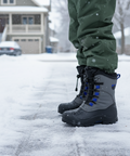 Person wearing gray winter boots with blue accents on a snowy ground.
